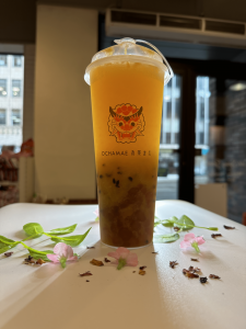 A glass of Passion Mango Tea with ice and fresh fruit pieces on top